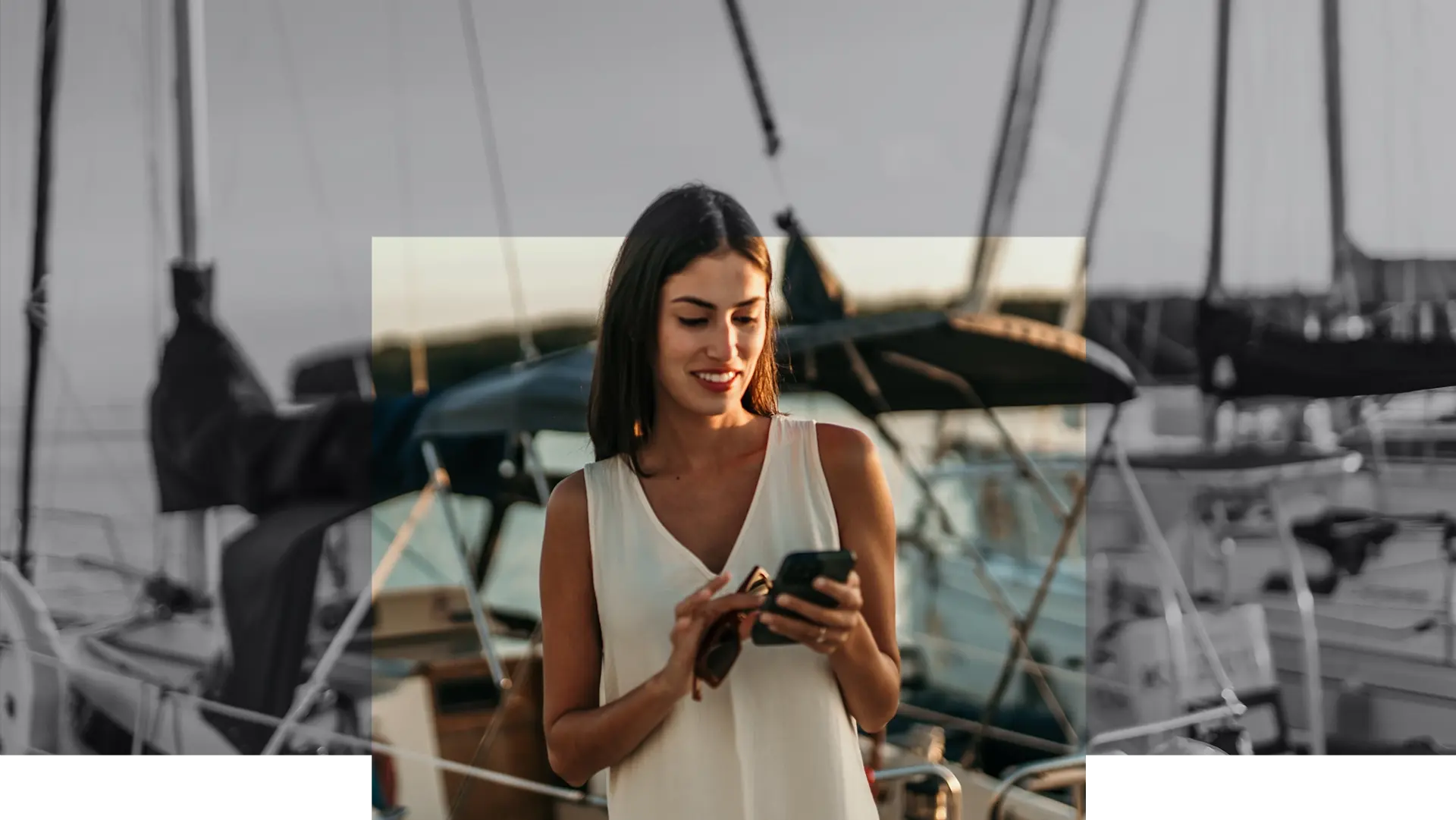 Private client checking her phone aboard a yacht at golden hour